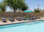 Thumbnail 1 of 10 - a swimming pool with lounge chairs and an umbrella