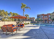 Thumbnail 25 of 26 - A pool area with chairs and umbrellas in front of a building.