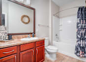 Thumbnail 15 of 22 - A bathroom with a toilet, sink, and a mirror at Overlook at Stone Oak Park Apartments, San Antonio