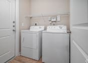 Thumbnail 16 of 22 - A small laundry room with a washer and dryer at Overlook at Stone Oak Park Apartments, San Antonio