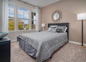 Thumbnail 14 of 22 - A bedroom with a large bed and a window overlooking a house at Overlook at Stone Oak Park Apartments, San Antonio