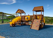 Thumbnail 9 of 22 - A playground with a yellow slide and a wooden structure at Overlook at Stone Oak Park Apartments, San Antonio
