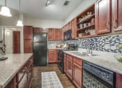 Thumbnail 8 of 19 - Kitchen with Wood Cabinets & Granite Countertops at Overlook at Stone Oak Park Apartments, San Antonio, Texas