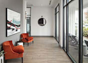 Thumbnail 22 of 48 - a hallway with two orange chairs and a mirror on the wall