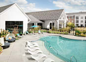 Thumbnail 33 of 48 - a swimming pool with white lounge chairs and a building in the background