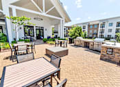 Thumbnail 44 of 48 - a patio with tables and chairs and a grill and a building