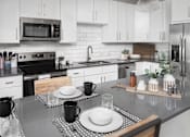Thumbnail 4 of 48 - a kitchen with white cabinets and black counter tops