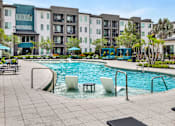 Thumbnail 19 of 60 - Resort pool with tanning ledge seating and cabanas at Avli At Crosstown Center Apartments, TAMPA, FL