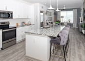 Thumbnail 24 of 60 - White kitchen with granite island and bar stools at Avli At Crosstown Center Apartments, TAMPA, 33619
