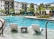 Thumbnail 1 of 60 - Pool with tanning ledge lounge chairs and table at Avli At Crosstown Center Apartments, TAMPA, Florida