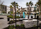 Thumbnail 13 of 60 - Outdoor patio with string lights and swimming pool at Avli At Crosstown Center Apartments, TAMPA, FL 33619