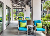 Thumbnail 22 of 60 - Covered patio with wicker seating and decorative pillows at Avli At Crosstown Center Apartments, TAMPA, Florida