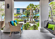 Thumbnail 2 of 60 - Covered patio with wicker seating and poolside views at Avli At Crosstown Center Apartments, TAMPA