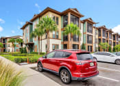 Thumbnail 18 of 46 - a red car parked in front of an apartment complex