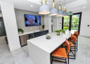 Thumbnail 39 of 46 - a kitchen with a large white island with orange chairs and a large tv on the wall