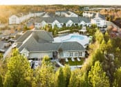 Thumbnail 1 of 54 - A large clubhouse building with a pool surrounded by trees.