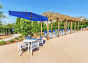 Thumbnail 28 of 54 - A row of lounge chairs and a picnic table on the pool sundeck near trees and bushes