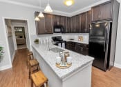Thumbnail 30 of 54 - Kitchen view with pendant lights and bar seating leading into a hallway towards a bedroom