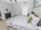 Thumbnail 20 of 54 - Bedroom with a slender tall window, ceiling fan, tan carpet, and doorway leading to a hallway