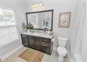 Thumbnail 39 of 54 - Bathroom with large vanity, mirror, toilet, bathtub, towel bars, and a tall window