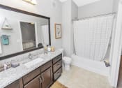 Thumbnail 31 of 54 - Full bathroom with hard floors, a large counter with wooden cabinetry, and bathtub shower combo