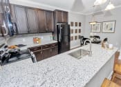 Thumbnail 18 of 54 - U-shaped kitchen with dark wooden cabinets and speckled countertops leading into the dining room