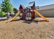 Thumbnail 29 of 54 - Gated playground with wood chips on the ground near trees