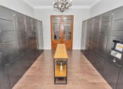 Thumbnail 26 of 54 - Mail room for package pick up with hanging chandelier, slender table in the middle and double doors