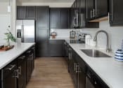 Thumbnail 78 of 78 - a large kitchen with black cabinets and white countertops and a sink