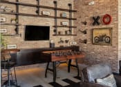Thumbnail 74 of 78 - a living room with a brick wall and a game table and a television