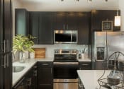 Thumbnail 5 of 78 - Luxury designer kitchen with dark wooden cabinets & stainless appliances in Charlotte, NC apartments