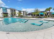 Thumbnail 1 of 32 - a resort style pool with chaise lounge chairs and umbrellas in front of an apartment