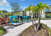 Thumbnail 28 of 32 - a patio with lounge chairs and a pool in front of an apartment building