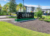 Thumbnail 30 of 32 - a sign in the middle of a grassy area with buildings in the background