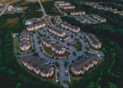 Thumbnail 16 of 54 - Aerial drone view of Riverstone Apartments with outdoor parking surrounded by lush green space