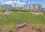 Thumbnail 30 of 37 - a swing set and two hammocks in a grassy area with apartment buildings in the background