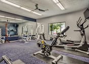 Thumbnail 12 of 29 - A gym with a variety of equipment including a rowing machine.
