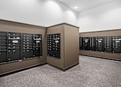 Thumbnail 22 of 36 - A room with a carpeted floor and a wall of mailboxes.