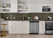 Thumbnail 27 of 36 - A modern kitchen with white cabinets and a black dishwasher.