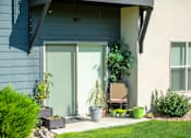 Thumbnail 11 of 20 - a patio with a chair and potted plants in front of a house