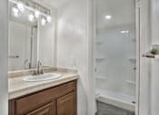 Thumbnail 14 of 15 - A bathroom with a sink, mirror, and shower.