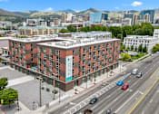 Thumbnail 3 of 36 - A large red brick building with a green sign on the side is in the middle of a busy street.