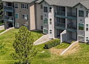 Thumbnail 5 of 29 - Apartment complex with a green lawn and trees.