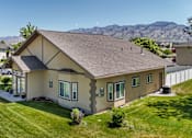 Thumbnail 9 of 29 - A house with a brown roof and a green lawn in front.
