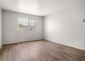 Thumbnail 27 of 32 - an empty living room with wood flooring and a window