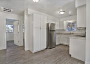 Thumbnail 3 of 14 - A kitchen with white cabinets and a stainless steel refrigerator.