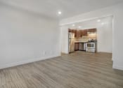 Thumbnail 9 of 15 - A kitchen area with wooden flooring and white walls.