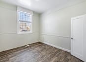 Thumbnail 10 of 19 - a bedroom with white walls and wood flooring and a window