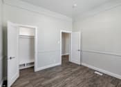 Thumbnail 11 of 19 - a bedroom with white walls and wood flooring and two doors