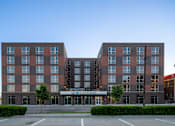 Thumbnail 1 of 36 - A large building with a parking lot in front of it.